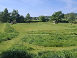 An outdoor area with grass, a playground, trees and a seating area at The Little Farmhouse in Carnforth
