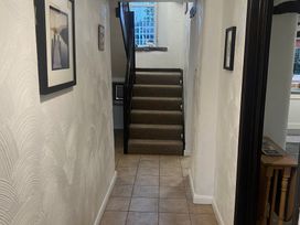 A hallway with staircase and photos on the walls at The Old Farmhouse at Brackenthwaite Farm Yealand Redmayne near Arnside