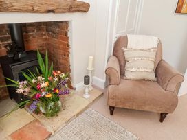 A living room with an armchair and a flower arrangement at Beehive in Beccles