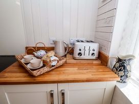 A kitchen counter with a kettle, toaster, teapot, cups, tray, and jar at Beehive in Beccles