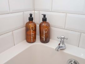 A bathroom with conditioner and shampoo bottles next to a tap at Beehive in Beccles