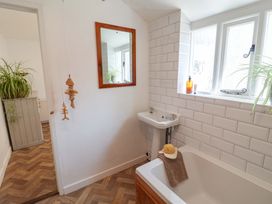 A bathroom with a bathtub, sink, and a mirror at Beehive in Beccles
