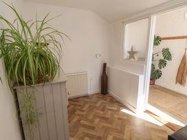 A hallway with a plant, radiator, and wooden cabinet at Beehive in Beccles