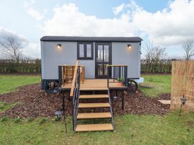 A shepherds hut with stairs leading to a small deck with a table and chairs at Shepherds Hut - Ash in Temple Bruer near Lincoln