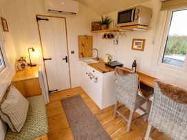 A compact kitchen area with wooden countertop chairs and a small sofa at Shepherds Hut - Ash in Temple Bruer near Lincoln