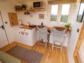 A small kitchen area with a sink microwave kettle two chairs and a wooden countertop at Shepherds Hut - Ash in Temple Bruer near Lincoln