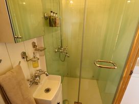 A small bathroom with a sink a towel a shower with glass door and shampoo bottles in shepherds hut ash in temple bruer near lincoln