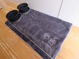A grey pet mat with paw prints and two collapsible bowls on a wooden floor at Shepherds Hut - Ash in Temple Bruer near Lincoln