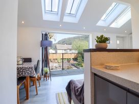 A dining area with table and chairs next to a balcony door with mountain view at Dola Pentre Du near Betws-Y-Coed
