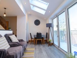 A dining area with a table and chairs next to large glass doors and a sofa with cushions in a living space at Dola in Pentre Du near Betws-Y-Coed