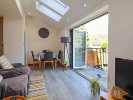 A dining area with a table and chairs next to an open door leading to a balcony in a living room at Dola in Pentre Du near Betws-Y-Coed