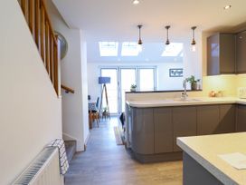 A kitchen with grey cabinets and a countertop next to stairs and a dining area with table and chairs at Dola in Pentre Du near Betws-Y-Coed