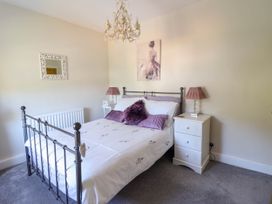 A bedroom with a metal bed frame white bedding purple pillows bedside tables with lamps and a chandelier at Dola in Pentre Du near Betws-Y-Coed