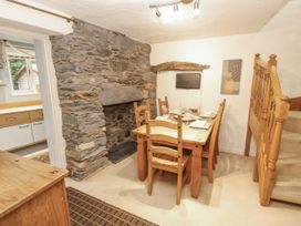 A dining room with a stone fireplace and wooden table and chairs at 2 Bens Row Backbarrow near Newby Bridge
