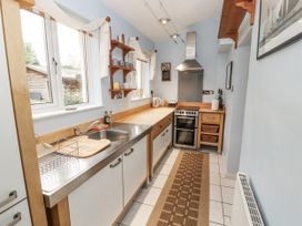 A kitchen with a countertop, sink, oven and shelves at 2 Bens Row Backbarrow near Newby Bridge