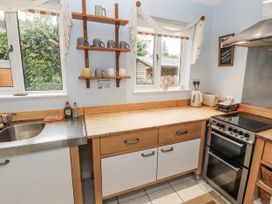 A kitchen with a sink, counter, oven, cabinets and shelves at 2 Bens Row Backbarrow near Newby Bridge
