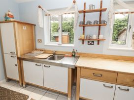 A kitchen with a sink and shelves holding mugs at 2 Bens Row Backbarrow near Newby Bridge
