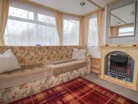 A sitting area with a patterned sofa cushions and a fireplace with a mirror above at Carnaby in South Chard