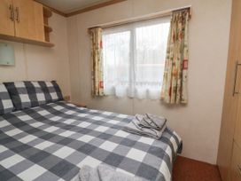 A bedroom with a bed covered in checkered bedding and towels on top next to a window with patterned curtains at Carnaby in South Chard