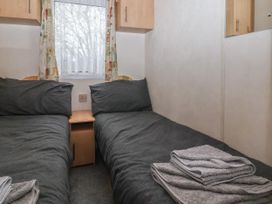 A small bedroom with two single beds with gray bedding a wooden nightstand between the beds and some folded towels on one bed at Carnaby in South Chard