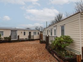Two beige mobile homes with small wooden porches and plants in gravel area at Carnaby in South Chard