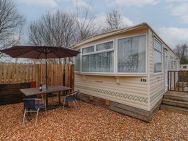 An outdoor seating area with a table umbrella and chairs next to a mobile home at Carnaby in South Chard