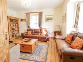 A living room with two brown leather sofas a wooden coffee table a bookshelf and framed pictures on the wall at Mor Iwerddon in Barmouth