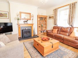 A living room with sofas a wooden chest coffee table a fireplace and a bookshelf at Mor Iwerddon in Barmouth