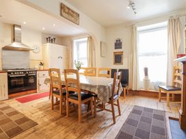A kitchen dining area with a wooden table and chairs a stove and cabinets at Mor Iwerddon in Barmouth