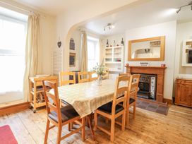 A dining room with a wooden table and chairs a fireplace and shelves with glassware at Mor Iwerddon in Barmouth