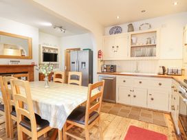 A kitchen with wooden dining table and chairs a refrigerator and kitchen cabinets at Mor Iwerddon in Barmouth