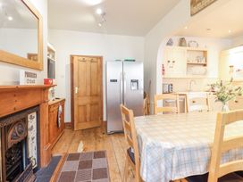 A kitchen dining area with a wooden table and chairs a double door refrigerator wooden cabinetry and a fireplace at Mor Iwerddon in Barmouth