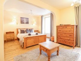 A bedroom with a wooden bed and matching furniture including two bedside tables a chest of drawers and a coffee table at Mor Iwerddon in Barmouth