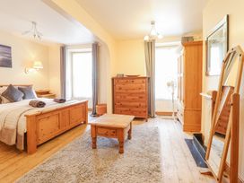 A bedroom with a wooden bed a chest of drawers a coffee table and a standing mirror at Mor Iwerddon in Barmouth