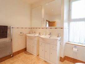 A bathroom with two sinks and mirrors next to a window with a towel rail at Mor Iwerddon in Barmouth