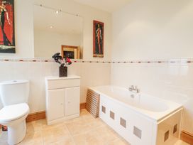 A bathroom with a toilet a bathtub a white cabinet and a mirror at Mor Iwerddon in Barmouth