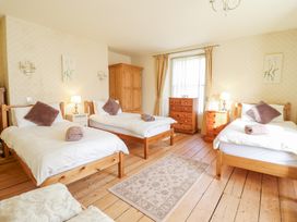 A bedroom with three single beds wooden furniture and a window at Mor Iwerddon in Barmouth
