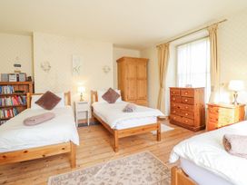 A bedroom with three single beds wooden furniture and a window with curtains at Mor Iwerddon in Barmouth