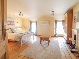 A bedroom with a wooden floor a bed a wooden cabinet a fireplace and a wooden table at Mor Iwerddon in Barmouth