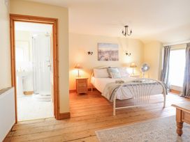 A bedroom with a double bed bedside tables lamps a fan and an en suite bathroom at Mor Iwerddon in Barmouth