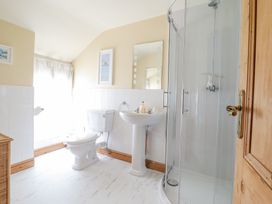 A bathroom with a toilet sink glass shower and a wicker basket at Mor Iwerddon in Barmouth