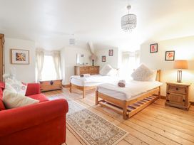 A bedroom with two single beds a red sofa wooden furniture and framed pictures at Mor Iwerddon in Barmouth