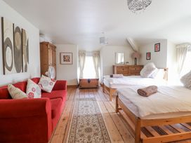 A bedroom with two wooden beds a red sofa a wooden chest and a wooden dresser at Mor Iwerddon in Barmouth
