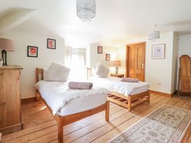 A bedroom with two single beds wooden furniture and wooden floor at Mor Iwerddon in Barmouth