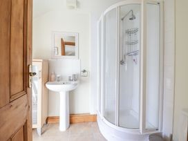 A bathroom with a glass shower enclosure a pedestal sink a wooden cabinet and a wooden door at Mor Iwerddon in Barmouth