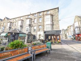 Street view with stone buildings benches plants and a clothing shop window at Mor Iwerddon in Barmouth