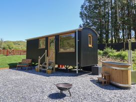 An outdoor area with a black corrugated small cabin wooden bench fire pit and wooden hot tub at Celyn in Bontddu near Dolgellau