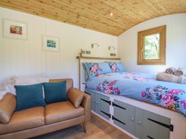 A bedroom with a floral bedspread a brown sofa and framed pictures on the wall at Celyn in Bontddu near Dolgellau
