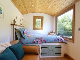 A bedroom with a floral bedspread a brown sofa and a large window at Celyn in Bontddu near Dolgellau