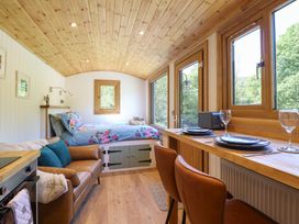 A small room with a bed a leather sofa and a dining counter with chairs at Celyn in Bontddu near Dolgellau